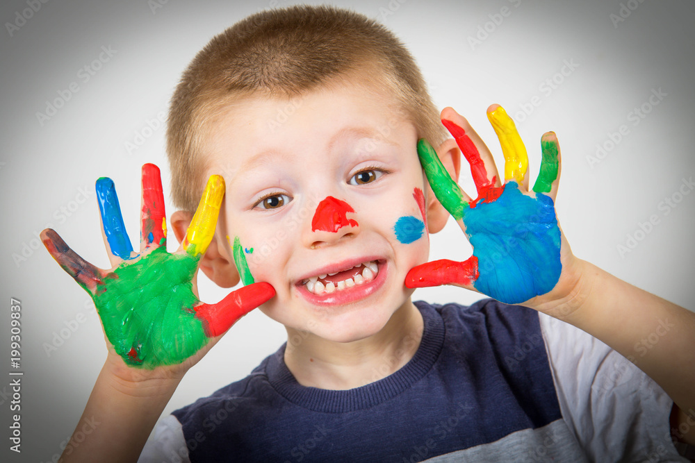 smiling little boy with hands painted in colorful paints smiling little boy with hands painted in colorful paints
