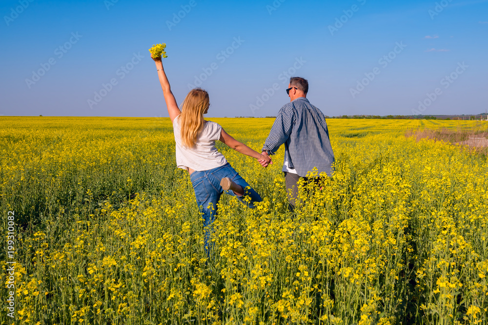 Joyful couple with open arms is walking through the field