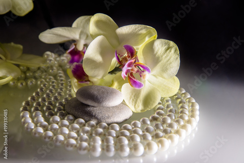 flat stones on a white glass on the background of yellow orchids 
