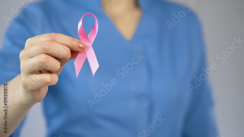 Doctor showing pink ribbon closeup, breast anticancer campaign, examination