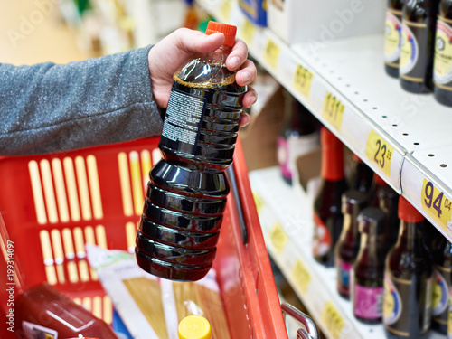 Soy sauce bottle in hand buyer at grocery store