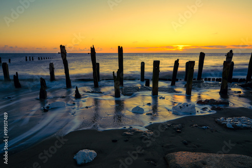 Twilight sky over soft motion sea and wooden posts. Spurn Point, East Yorkshire, UK.