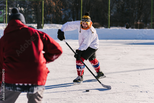 men play hockey on the rink during the day