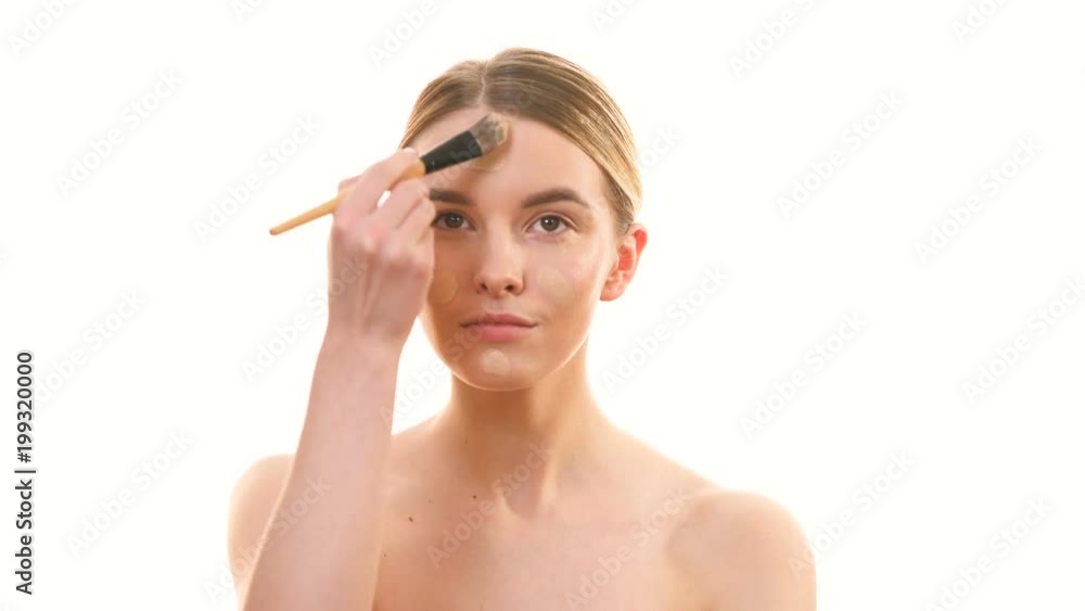 The beautiful woman applying the powder on her face on the white background The beautiful woman applying the powder on her face on the white background