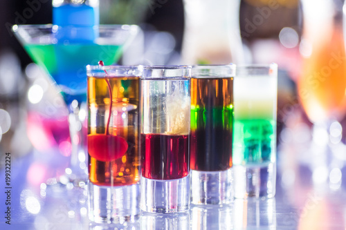 Multicolored multilayered cocktails on the bar in the fire © artem_goncharov
