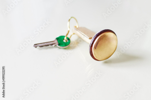 Steel key with golden keychain isolated in white. © Armando