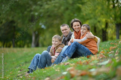 Happy smiling family in autumn forest sitting 