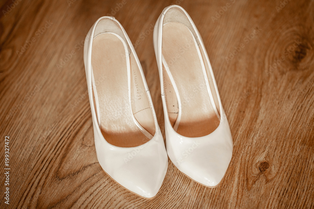 Fototapeta premium white women's wedding shoes on wooden floor