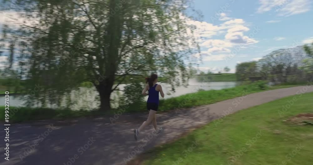 A panning shot of a fit woman jogging in the park on a sunny day. A panning shot of a fit woman jogging in the park on a sunny day.