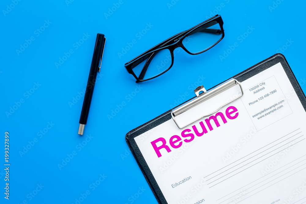 Looking for work concept. Resume on pad near pen and glasses on blue background top view space for text Looking for work concept. Resume on pad near pen and glasses on blue background top view space for text