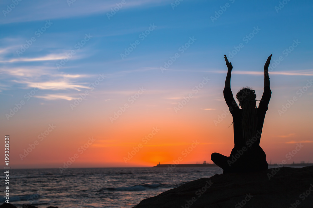 Meditation woman yoga silhouette. Sea during amazing sunset. Fitness and healthy lifestyle.