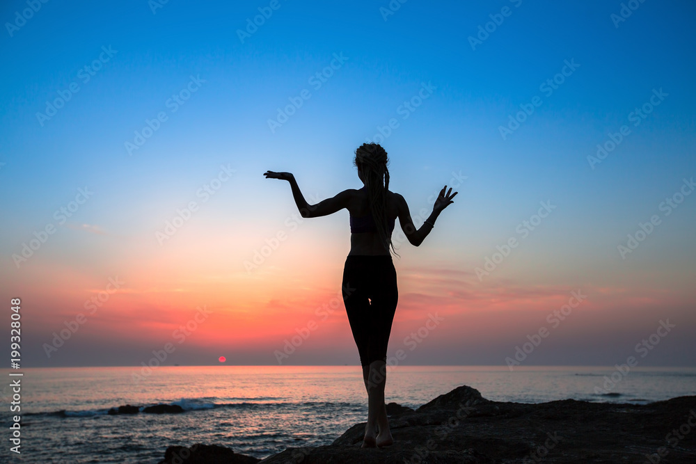 Fitness woman silhouette on the sea during amazing sunset.  Healthy lifestyle.