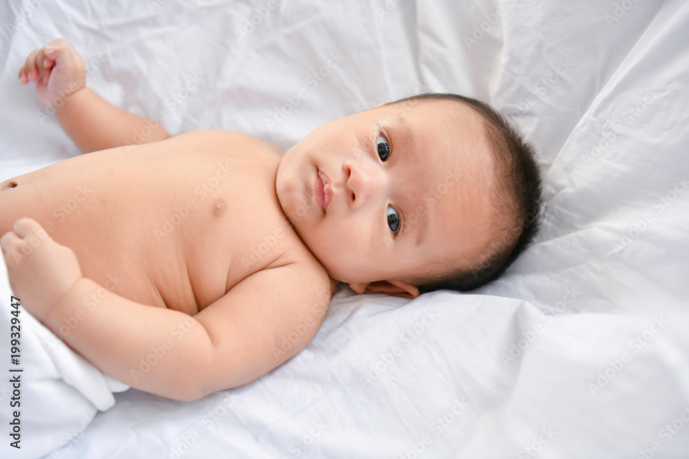 Newborn Concept. Mother and child on a white bed. Mom and baby boy playing in bedroom. Parent and little kid relaxing at home. Family having fun together. Newborn baby is fussing and crying. Newborn Concept. Mother and child on a white bed. Mom and baby boy playing in bedroom. Parent and little kid relaxing at home. Family having fun together. Newborn baby is fussing and crying.