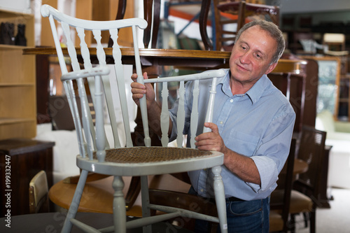 Mature male is choosing old chair for home photo