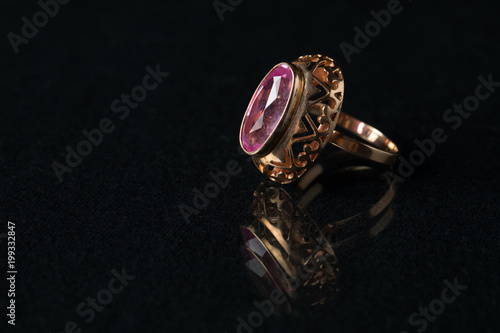 Golden ring with a ruby on a black background