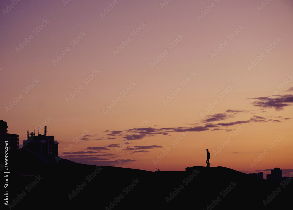 Silhouette people standing on hill at sunset time over city. 