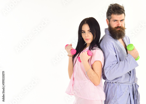 Couple, family do sports in morning, full of energy. Sporty lifestyle concept. Girl and man with dumbbells, morning exercises. Couple in love in pajama, bathrobe stand isolated on white background.