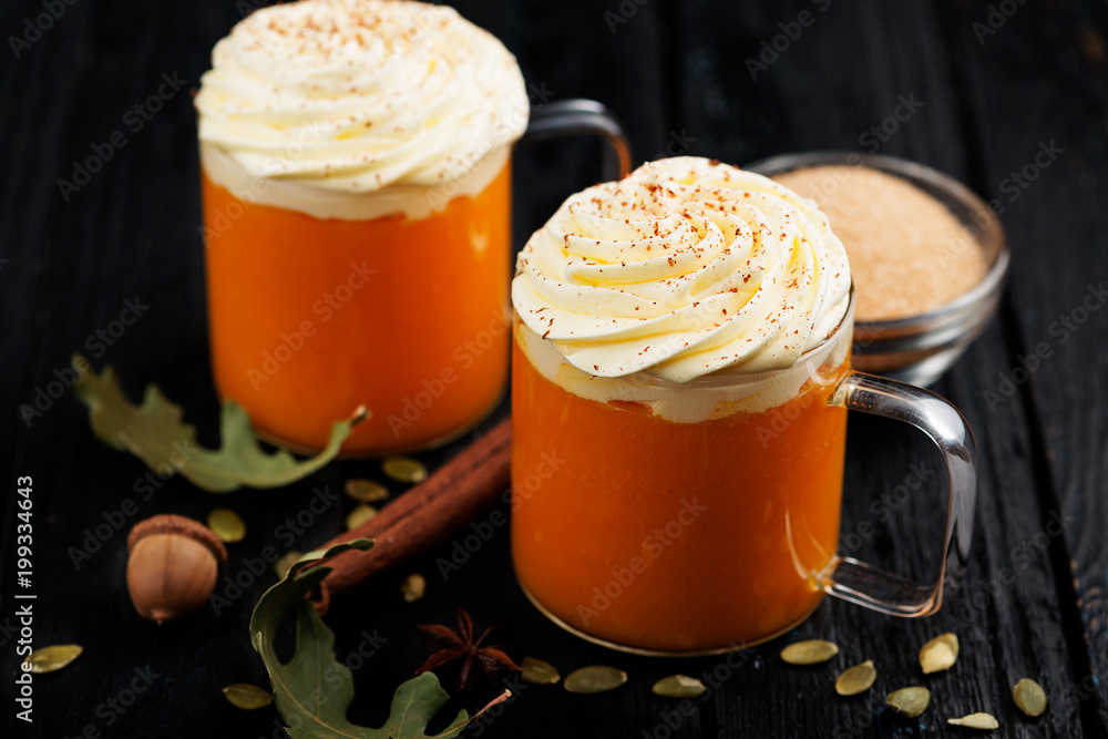 Pumpkin smoothie, spice latte with whipped cream on top on dark  wooden background.