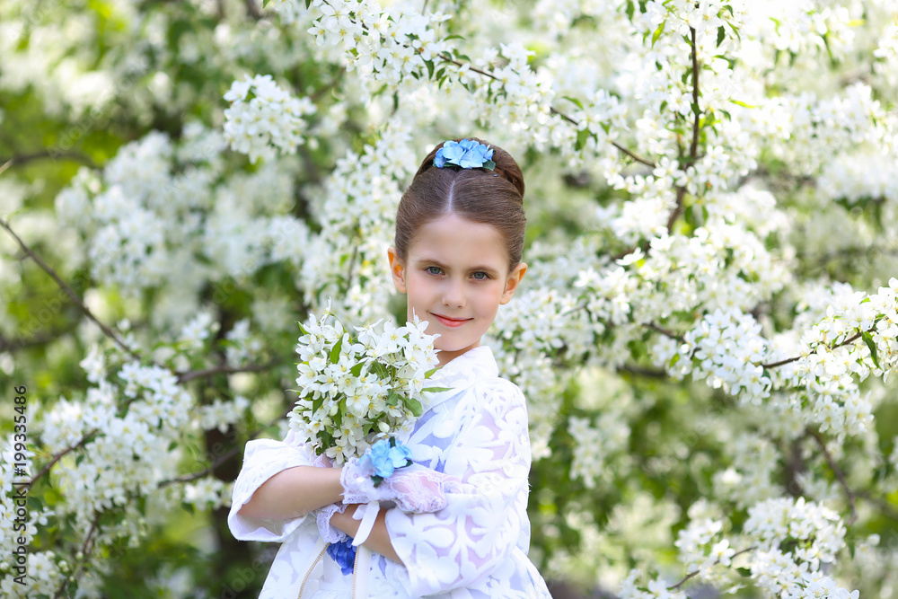 Sweet beautiful girl on the background of blooming apple trees in a park on a holiday in a smart dress with a fashionable hairstyle Sweet beautiful girl on the background of blooming apple trees in a park on a holiday in a smart dress with a fashionable hairstyle