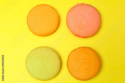 Delicious four multicolored macaroon on a yellow background