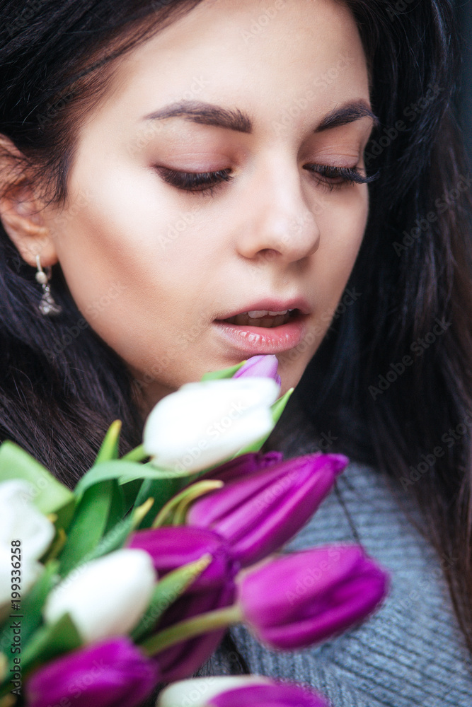 Close-up portrait of young beautiful brunette woman with tulips