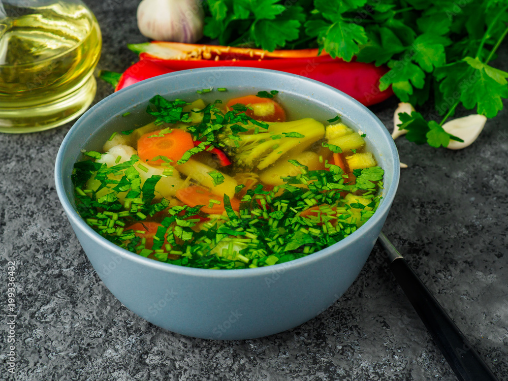 Healthy spring vegetable dietary vegetarian soup, gray concrete background, side view, close up. Healthy spring vegetable dietary vegetarian soup, gray concrete background, side view, close up.