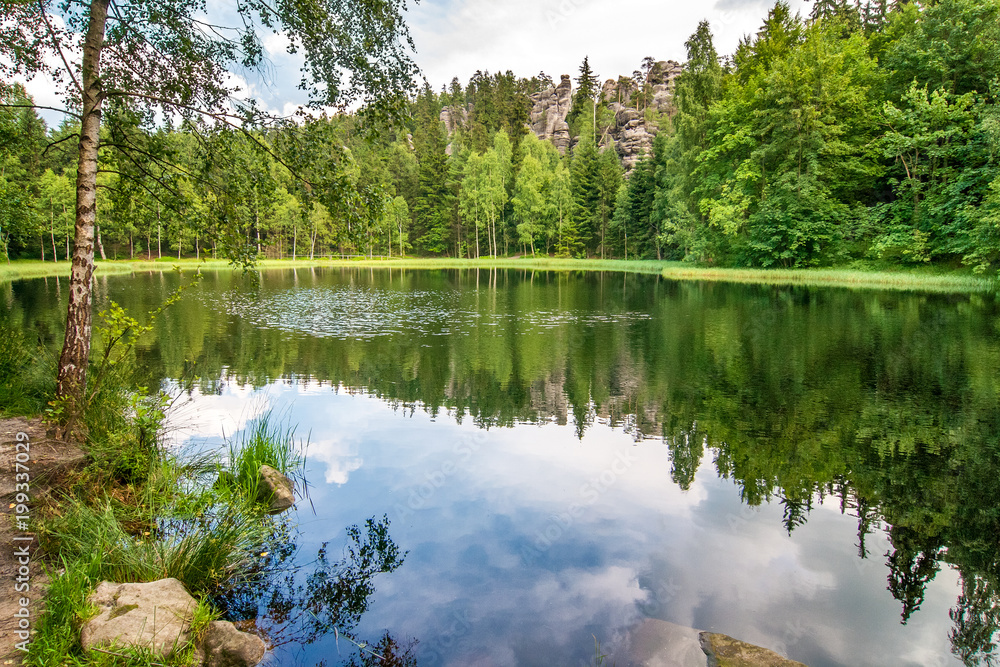 Lake with a reflection of blue cloudy sky. The Black Pond in national nature reserve Adrspach-Teplice Rocks, Czech republic, Europe. Lake with a reflection of blue cloudy sky. The Black Pond in national nature reserve Adrspach-Teplice Rocks, Czech republic, Europe.