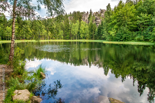 Lake with a reflection of blue cloudy sky. The Black Pond in national nature reserve Adrspach-Teplice Rocks, Czech republic, Europe.