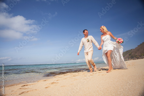 Wedding couple just married holds hands and walking at beach