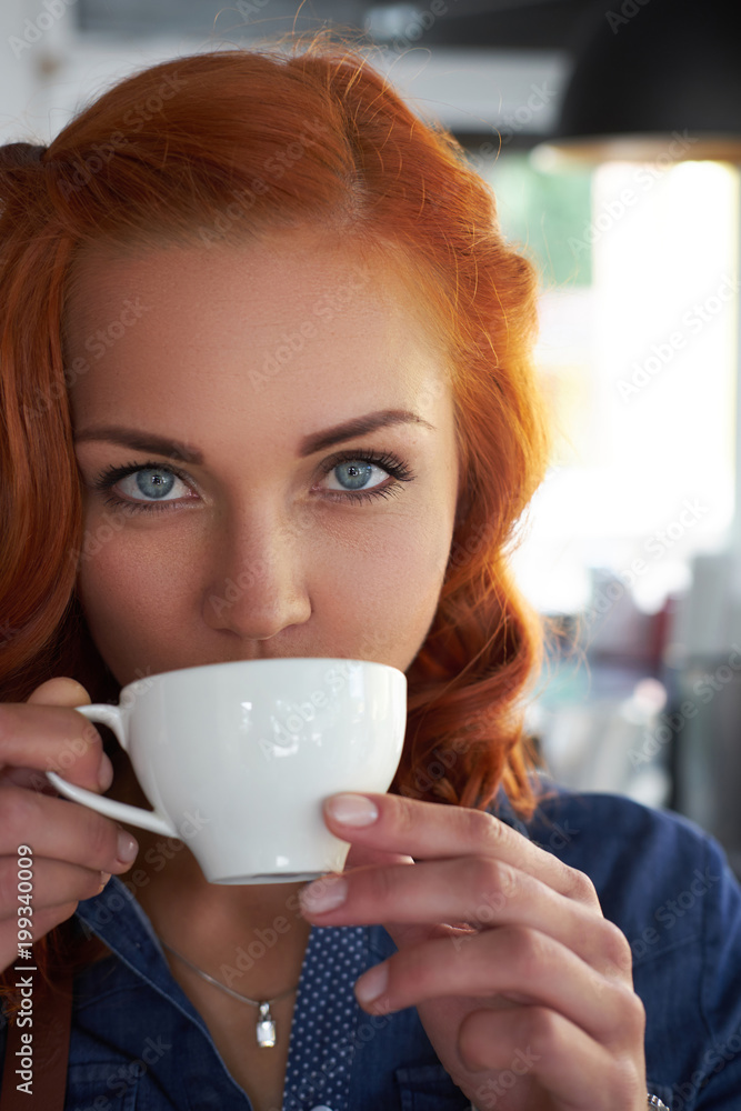 A beauty redhead female barista drinks a coffee, at the coffee shop. A beauty redhead female barista drinks a coffee, at the coffee shop.
