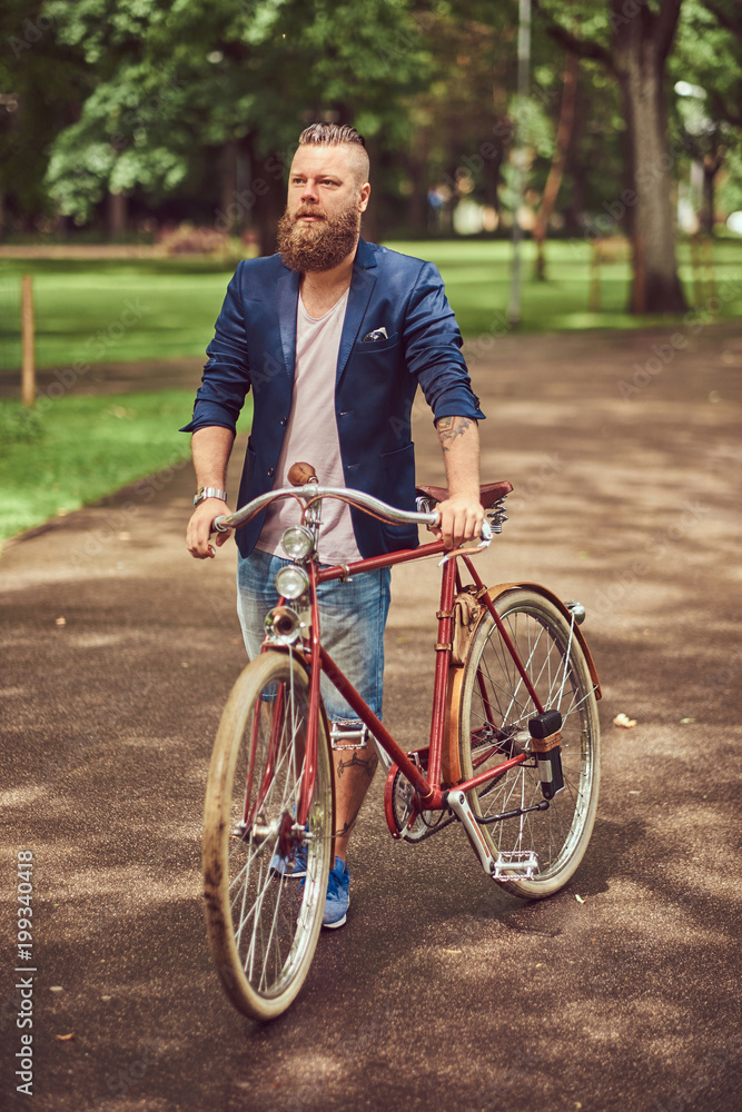 Male dressed in casual clothes, walking with a retro bicycle in a city park. Male dressed in casual clothes, walking with a retro bicycle in a city park.