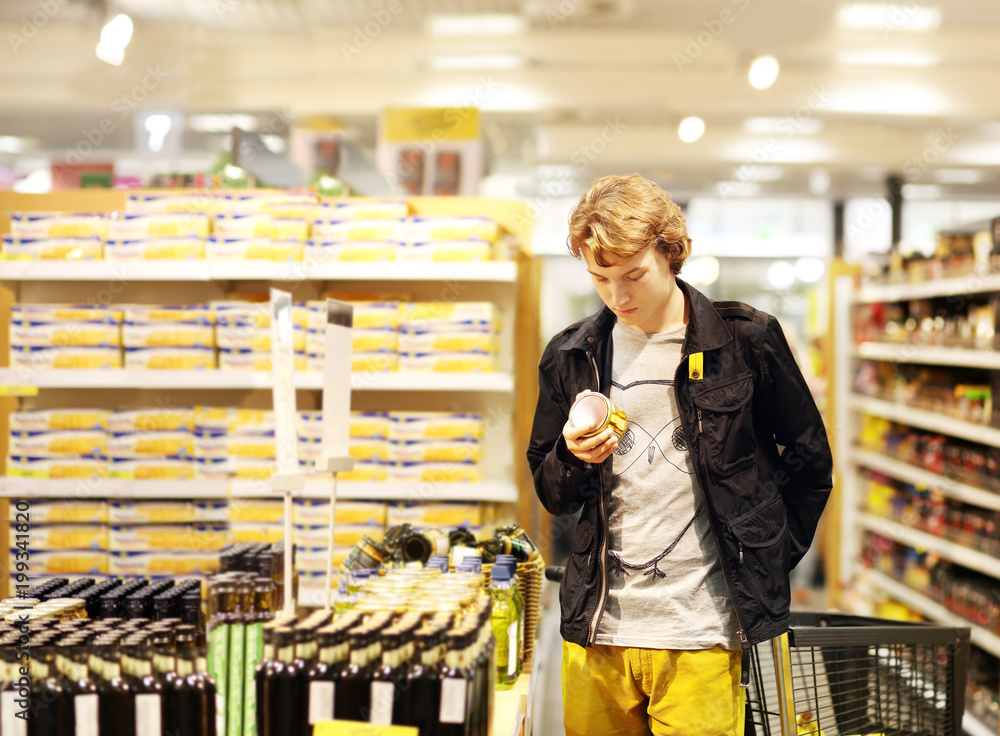 Man shopping in supermarket, reading product information