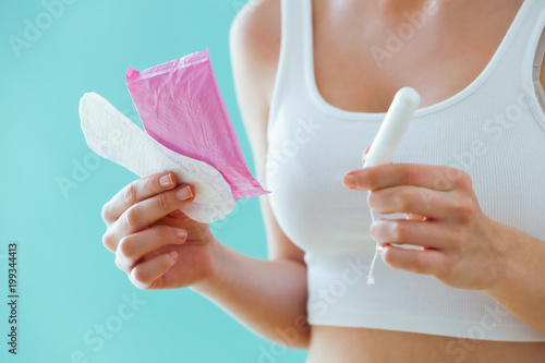 Young woman with a menstrual compress and a tampon on blue background. photo