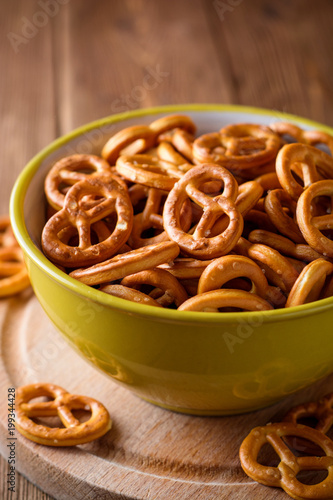 Mini pretzels with salt in a bowl on wooden background