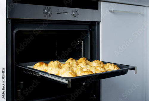 Homemade profiteroles in the oven. Process of baking cookies, French dessert, confectionery background.  photo