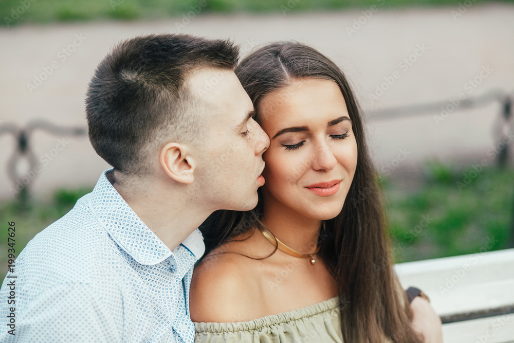 Happy young couple in love sitting on a park bench and hugging Happy young couple in love sitting on a park bench and hugging