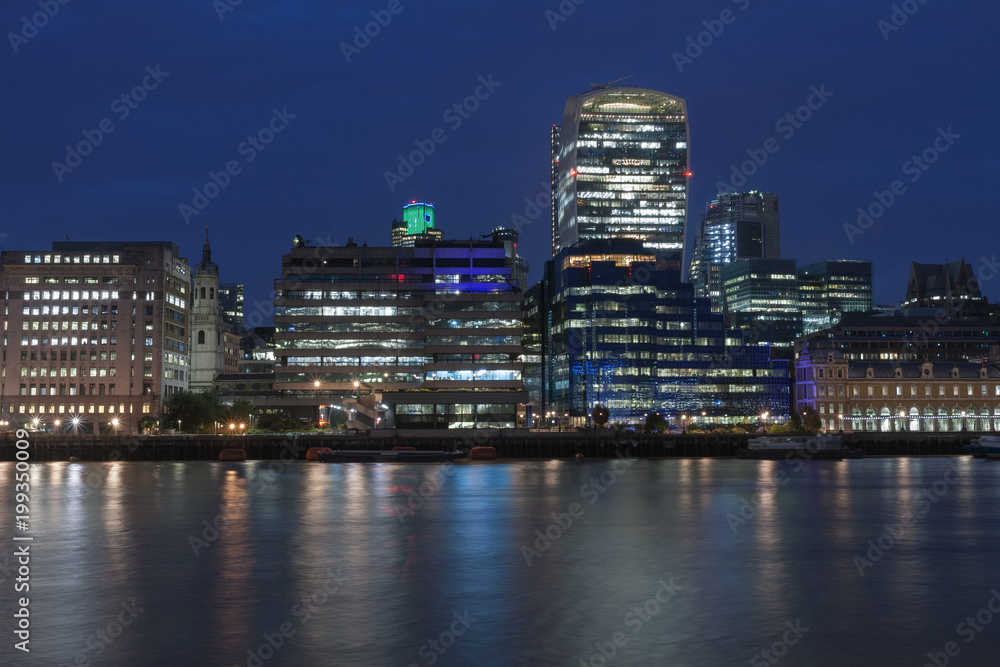 Thames embankment and london skyscrapers in City of London in the night.