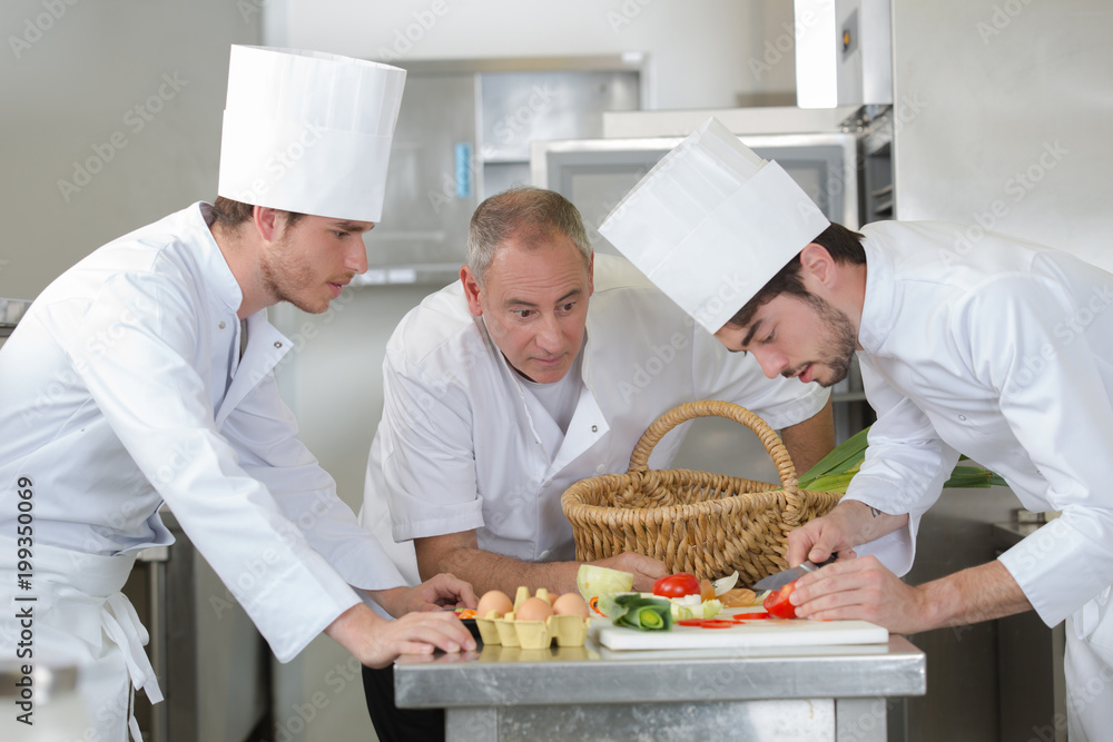 chief chef watching his assistant garnishing a dish chief chef watching his assistant garnishing a dish