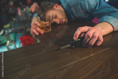 Drunk driver sleeping on counter. He holding key in hand. He locating in bar photo