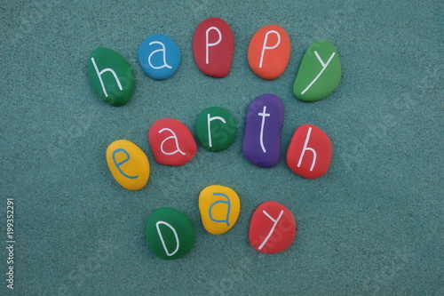 Happy Earth Day celebrated with multicolored sea stones over green sand