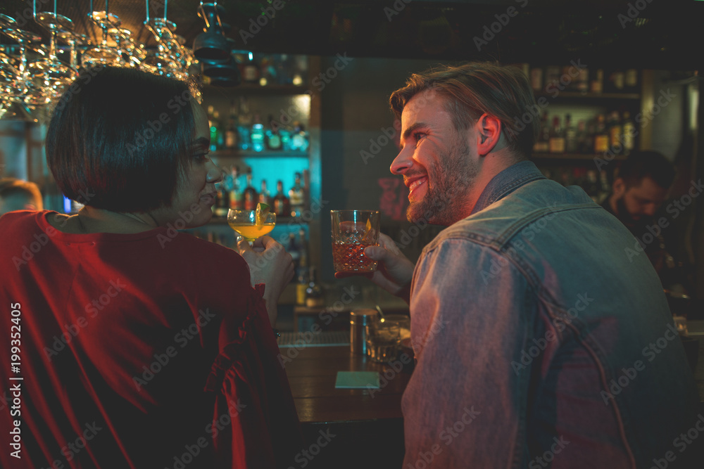 Side view cheerful female talking with happy man. Glad couple drinking alcohol beverage in bar concept