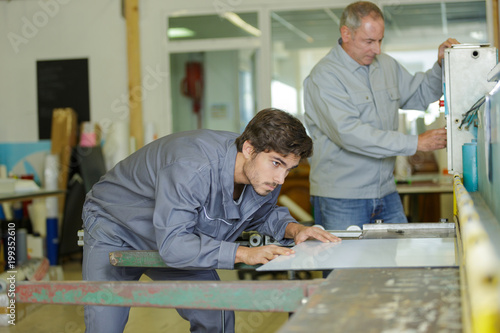 male manual workers examining sheet metal at industry © auremar