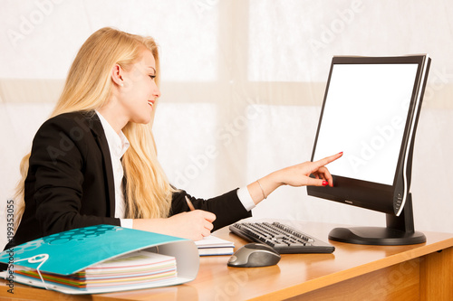 Beautiful business woman works in her office looks into monitro screen