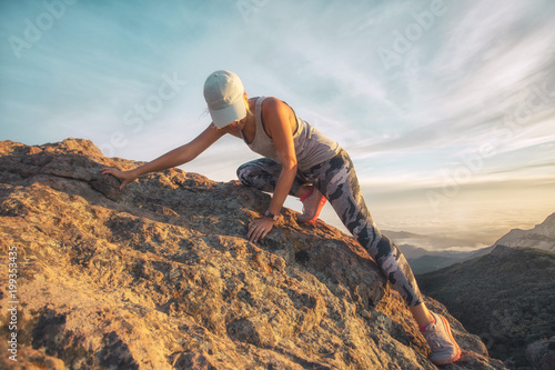 A young woman climbing a steep rocky mountain high above the sea level at Sandstone Peak, Malibu, California
