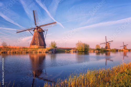 Scenic sunset landscape with windmill, blue sky and reflection in the water. Traditional dutch countryside, famous village of mills Kinderdijk, Netherlands (Holland)