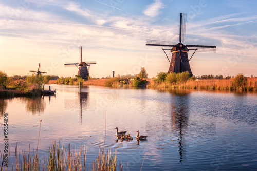 Scenic sunset landscape with windmill, blue sky and reflection in the water. Traditional dutch countryside, famous village of mills Kinderdijk, Netherlands (Holland)