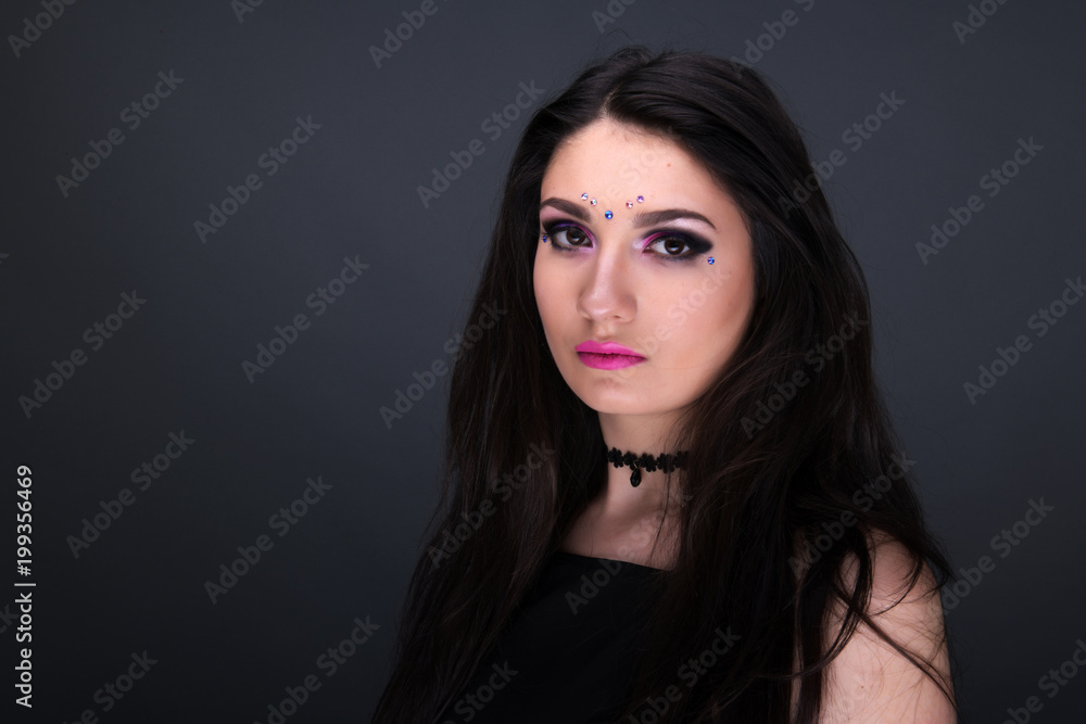 Close up face. Young arabic woman in black sexy dress, isolated on gray background