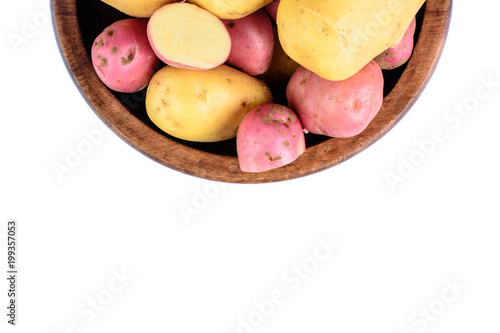 Raw potatoes in wooden bowl. Isolated close up food photo from above.