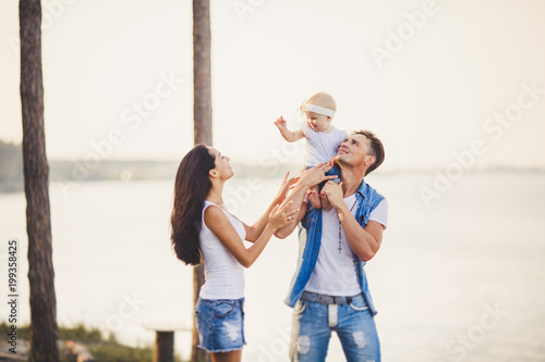 Family Holiday In Nature Three People Mom Dad Daughter Spend One Year On Cliff Overlooking Sea Young People Play Around And Laugh Fashionable Beautiful People Dressed In Stylish Denim Clothes Stock Photo