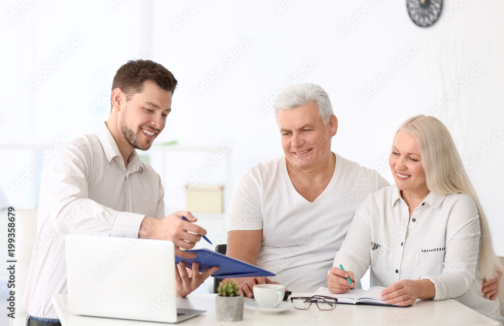 Mature couple discussing pension plan with consultant in office Mature couple discussing pension plan with consultant in office